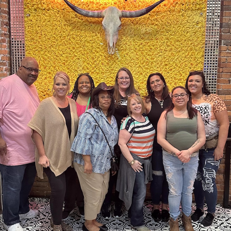 Smiling group in front of a yellow wall